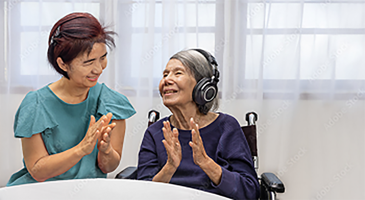 Caregiver and patient doing music therapy using headphones at a table