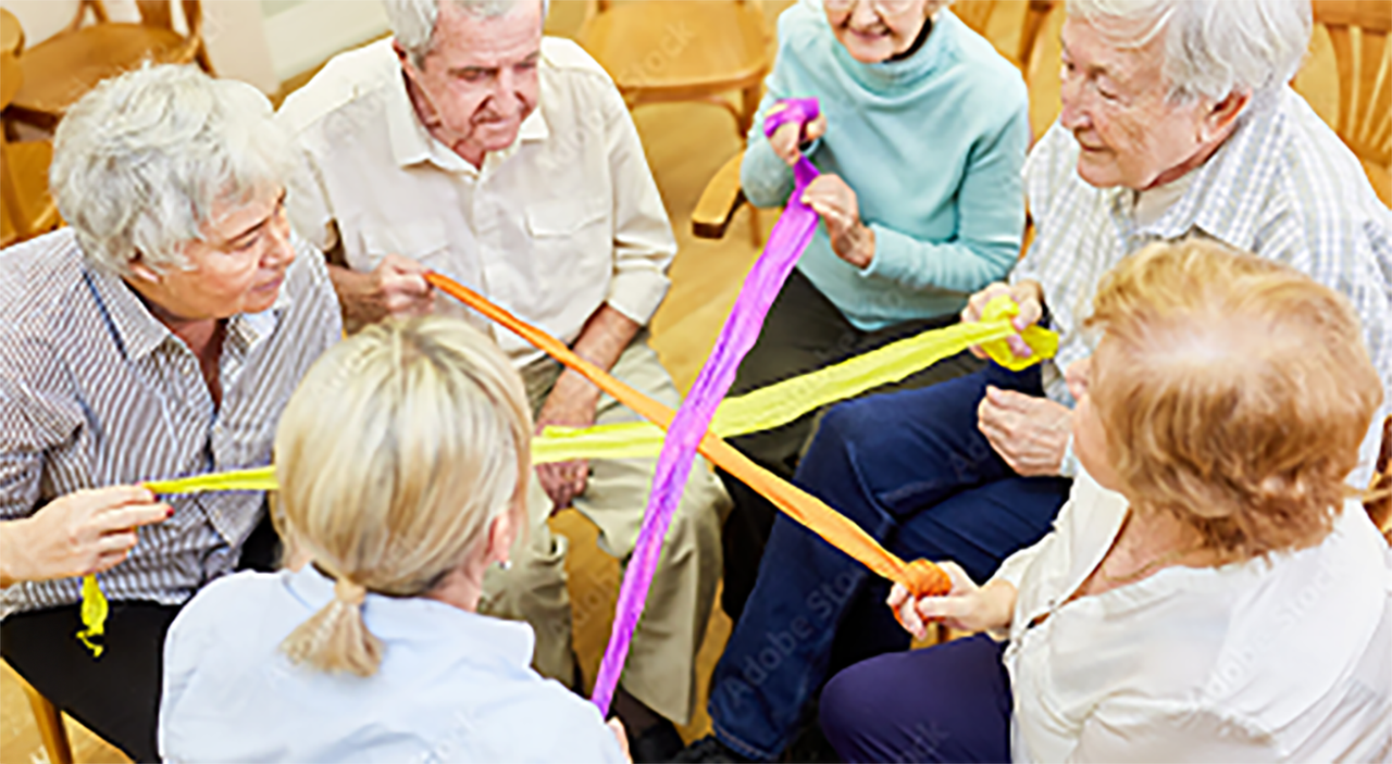 A group of patients and a caregiver using an exercise band for movement therapy